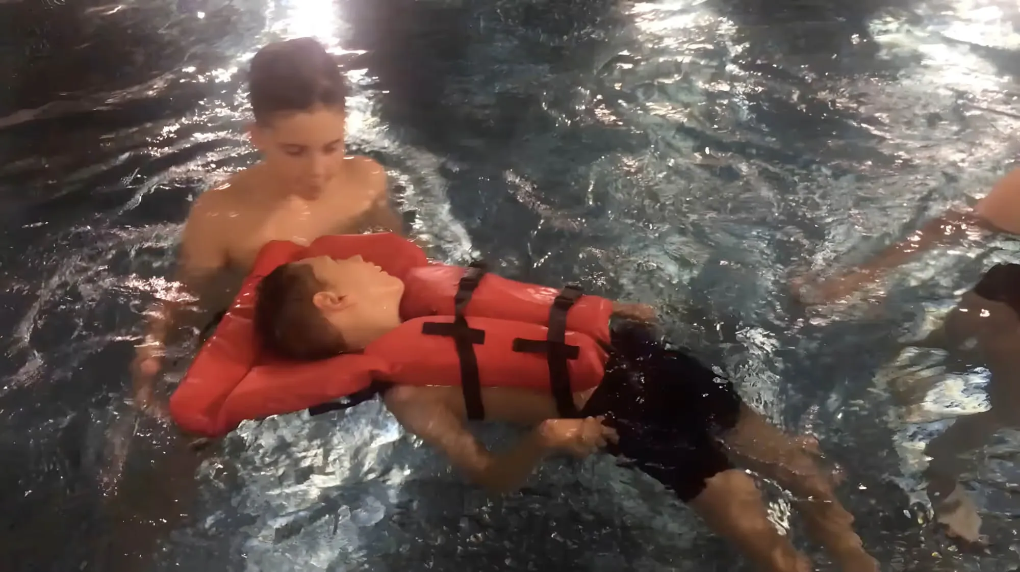 Mikkel flyter i vannet med redningsvest, sammen med Lena.