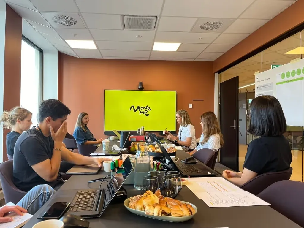 Designere og fagfolk rundt et bord i workshop om MoveMe.